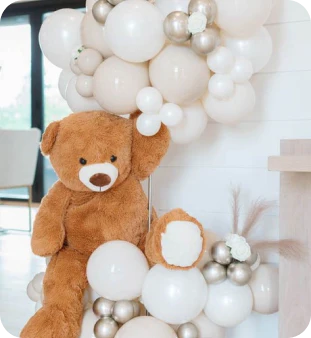 a big teddy bear with white and silver balloons