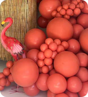 a display of salmony-orange balloons of many size with a flamingo and a bamboo background