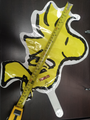 Un globo de papel de aluminio de 14,5" Anagram/MD Airfill Only Mini Shape Woodstock Snoopy Peanuts el Explorador descansa sobre una superficie oscura, con una cinta métrica que muestra que su longitud es de unas 16 pulgadas (40 cm). Los palos se venden por separado.