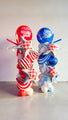 Dos arreglos de globos altos con Tuftex 24" Star USA Patriotic Picnic Gingham Star Foil Balloons en rojo, blanco y azul. Cada uno está decorado con globos en forma de estrella; uno dice "Red White New", el otro "Stars and Stripes".