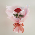 A single red rose is enclosed in a BB-Custom 8" Wide Neck BOBO Balloon (for filling with toy), wrapped in pink and iridescent paper, and finished with a pink satin ribbon—an elegant gift using this pre-stretched, heat-sealable balloon.